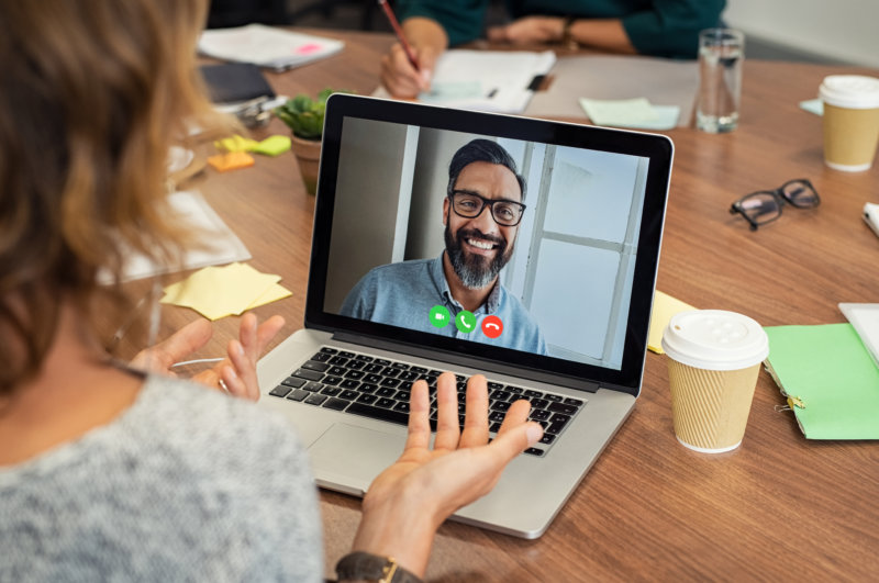 Image of a woman on a video call with a bearded man, using her laptop, web conferencing